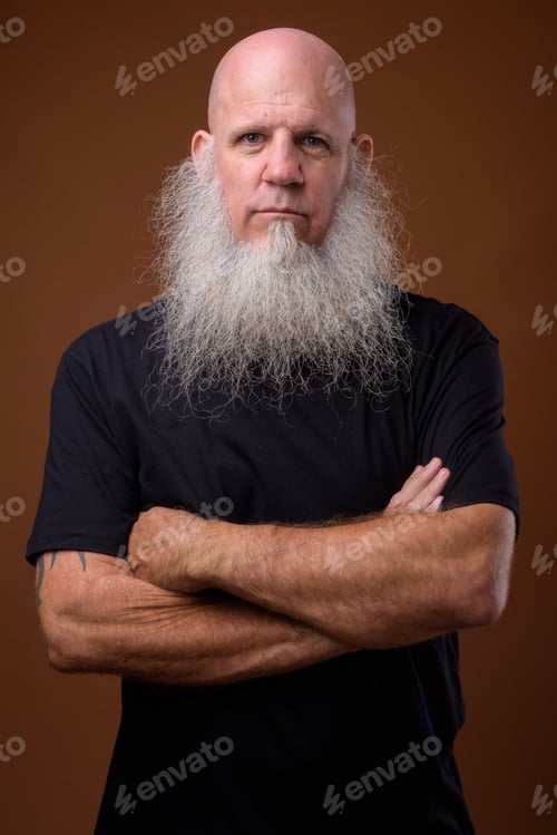 Preview: Mature bald man with long gray beard against brown background