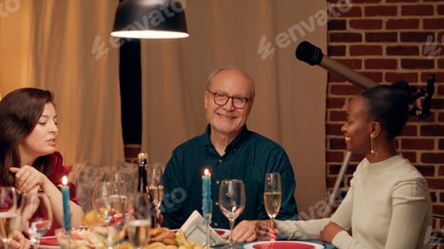 Preview: Cheerful senior man talking with young woman while at Christmas dinner table