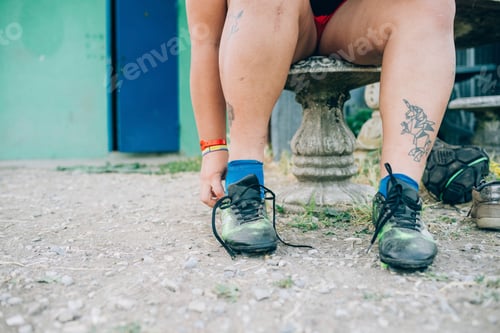 Preview: Tying up the laces on a pair of wellworn green shoes.