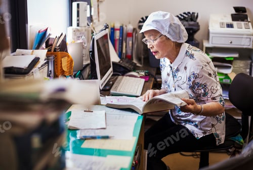 Preview: A mature woman at a desk in the office of a fast food unit and noodle production factory.