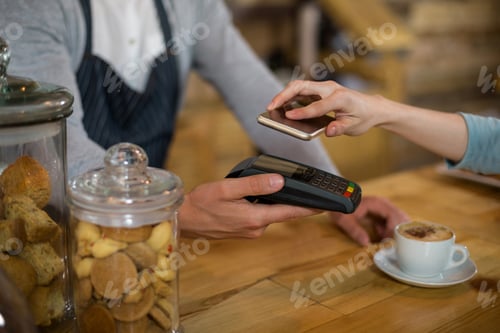 Preview: Woman paying bill through smartphone using NFC technology