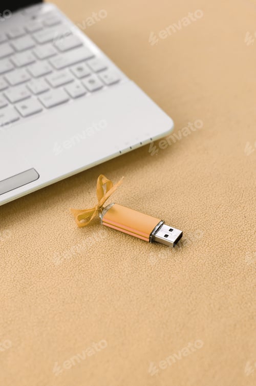 Preview: Orange usb flash memory card with a bow lies on a blanket of soft and furry light orange