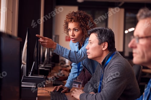 Preview: Teacher With Group Of Mature Adult Students In Class Working At Computers In College Library