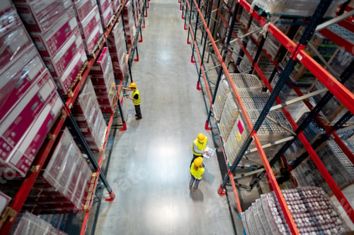 Preview: Warehouse managers consult plans using laptop, above view
