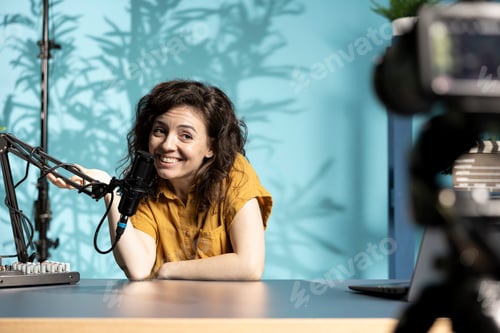 Preview: Joyous woman films vlog with high tech gear in studio, speaking into microphone