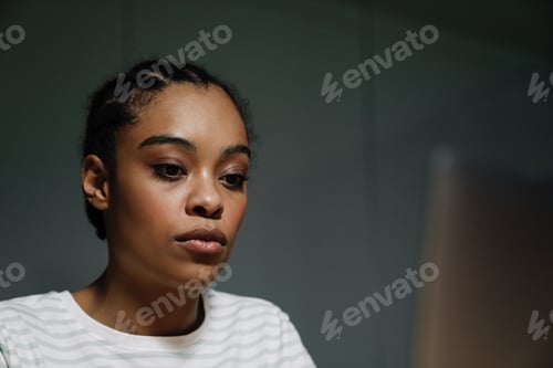 Preview: Black young woman using laptop while working in office