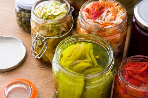 Preview: Preserved vegetables fermenting in glass jars on wooden table