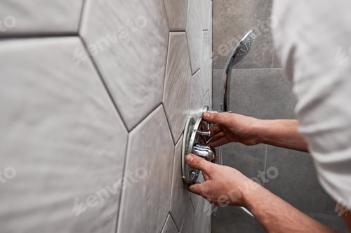 Preview: Male plumber hands installing shower faucet handle in bathroom.
