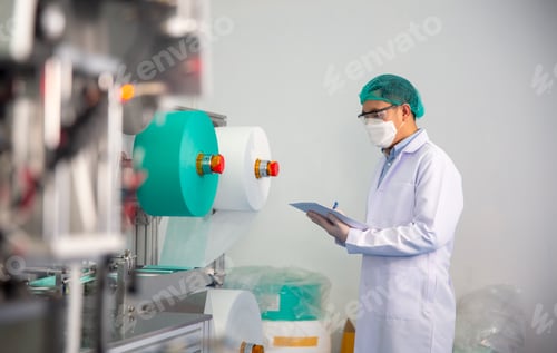 Preview: Mid adult male engineer examining machine part on a production line in a factory.