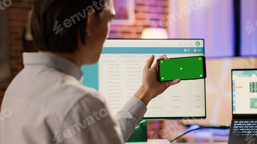 Preview: Entrepreneur looking at horizontal greenscreen on smartphone