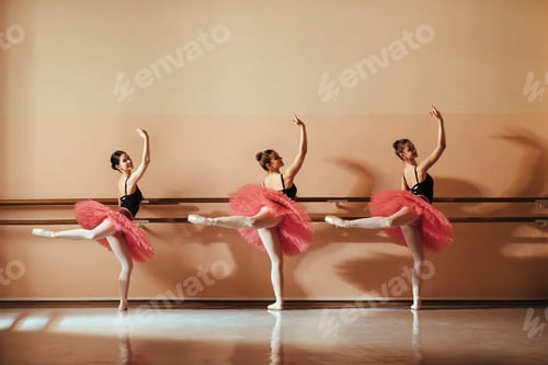 Preview: Smiling teenage ballerinas holding on barre while dancing at ballet studio.
