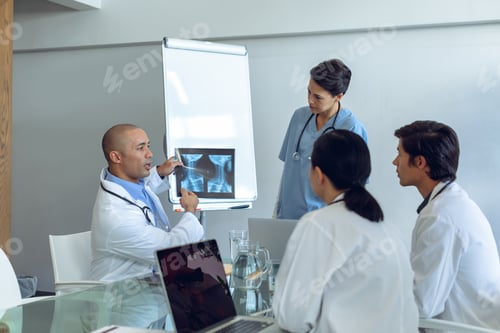 Preview: Diverse medical team discussing over x-ray report at the table of conference room