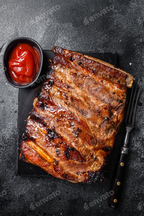 Preview: Full rack of BBQ grilled pork spare ribs on a marble board. Black background. Top view