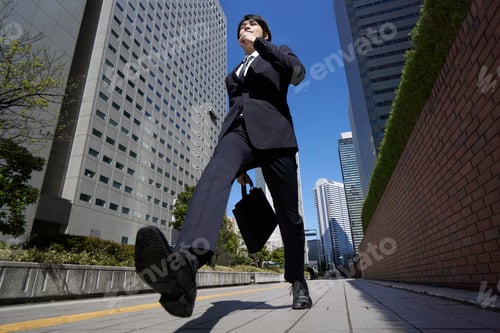 Preview: A Japanese male businessman walks briskly through an office district.