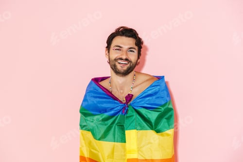 Preview: Young shirtless man wearing rainbow flag laughing and looking at camera