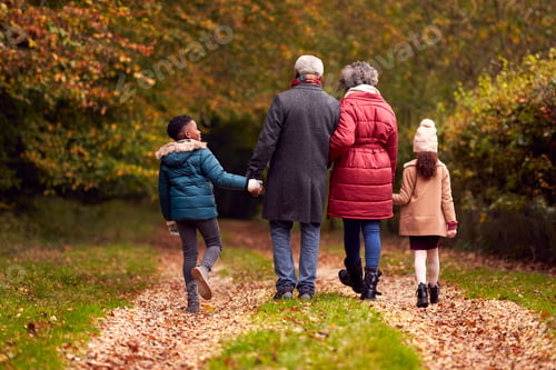 Preview: Rear View Of Grandparents Holding Hands With Grandchildren On Walk Through Autumn Countryside