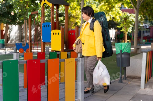 Preview: Woman carrying violin case walking past playground