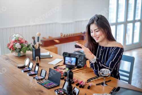 Preview: Beautiful young asian blogger with makeup cosmetics recording video at home. Teaching and selling pr