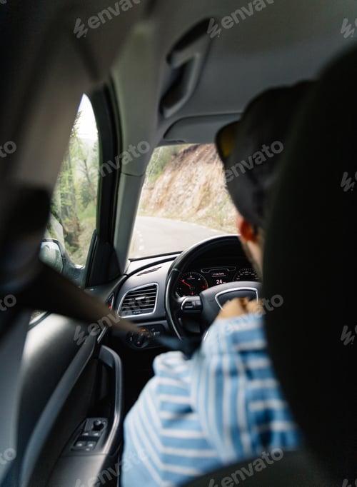 Preview: Man driving car while being on a day road trip.