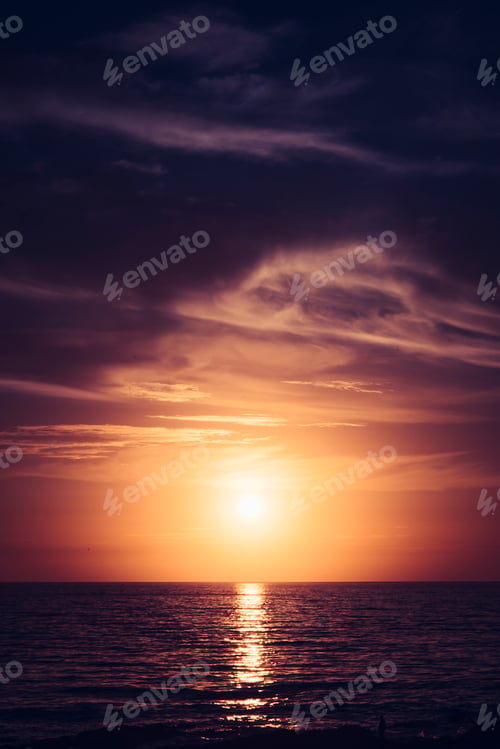 Preview: the sun sets over the beach in a purple and dramatic sky