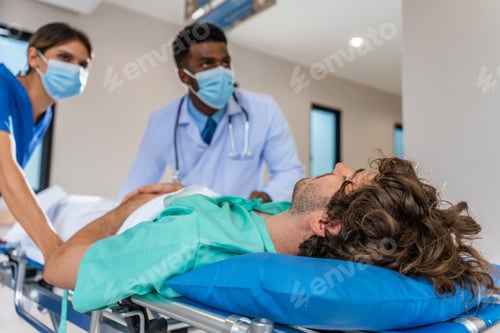 Preview: Group of diverse doctors moving seriously injured patient in hospital.