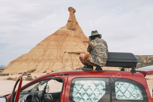 Preview: Traveler sitting on top of a van taking photos of the rocky landscape of the Navarra desert