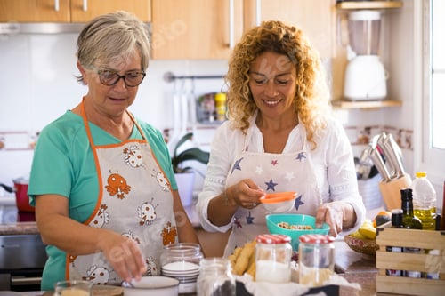 Preview: grandma and daughter at home cooking and smiling - enjoying and have fun indoor together