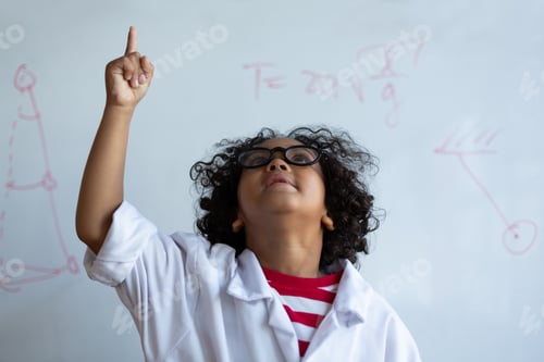 Preview: Schoolboy pointing finger up while standing in front of the white board in the laboratory at school