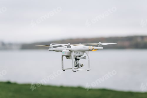 Preview: White quadrocopter is flying high in the air, taking photos, recording footage from above.