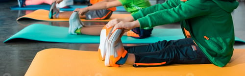 Preview: Cropped view of children stretching on fitness mats in sports center, panoramic shot