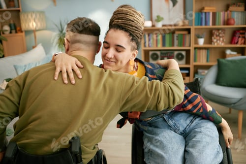Preview: Young Woman and Man with Disability Hugging in Living Room