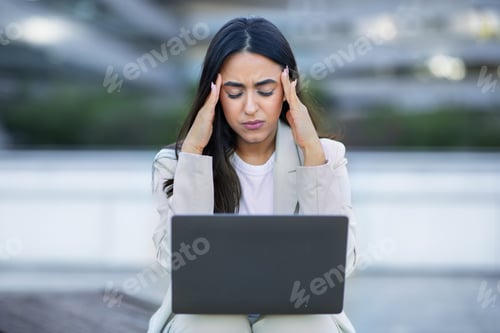 Preview: Unhappy Latin Businesswoman With Laptop Touching Temples Having Headache Outdoor
