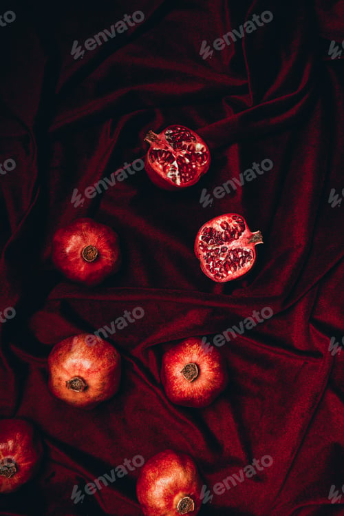 Preview: top view of arranged pomegranates on red velvet fabric background