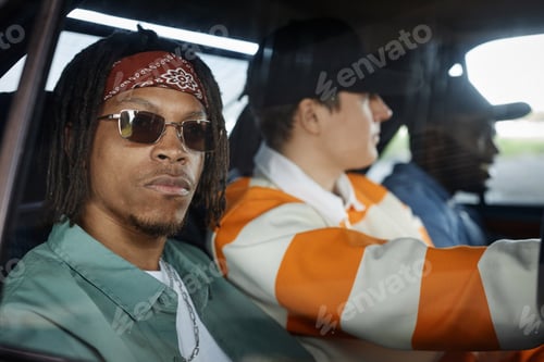 Preview: Young African American man in sunglasses and casual attire sitting in car