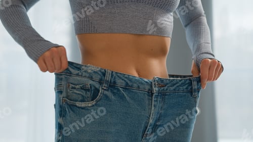 Preview: Female checking measure slim abdominal waist unrecognizable healthy fit woman girl wearing old big