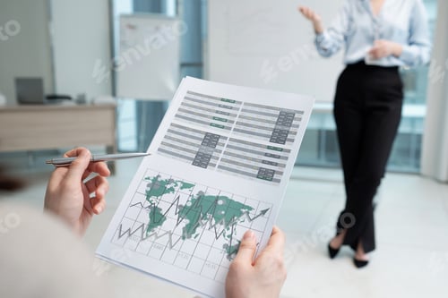 Preview: Hands of young female economist pointing at financial document with graphs