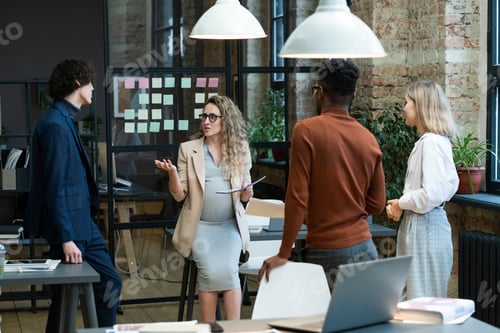 Preview: Pregnant businesswoman talking to her employees at office