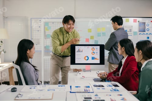 Preview: Asian businesspeople having meeting using charts and graphs on computer screen
