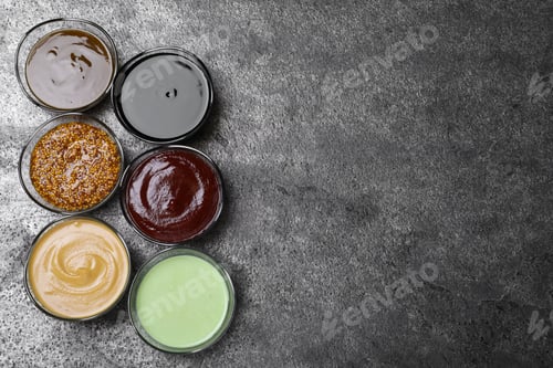 Preview: Many different sauces on grey table, flat lay. Space for text