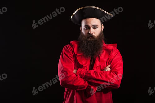 Preview: Handsome bearded man dressed up like a pirate for halloween carnival keeping his arms crossed and