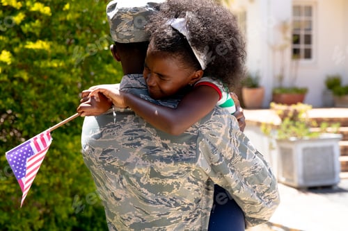 Preview: African American male soldier holding his daughter with a US flag in his arms