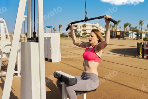 Preview: Mature woman doing sports exercises on outdoor simulators