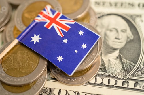 Preview: Stack of coins with Australia flag and US dollar banknotes.