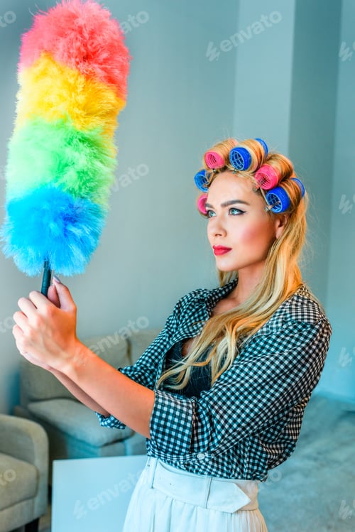 Preview: attractive blonde housewife in curlers cleaning house with duster