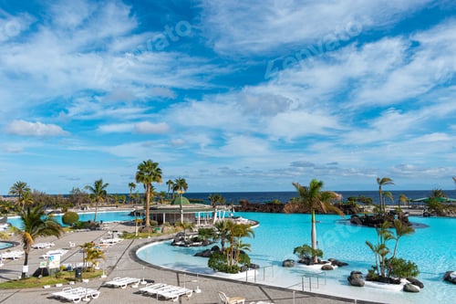 Preview: Idyllic view of a tropical resort with palm trees under a cloudy sky