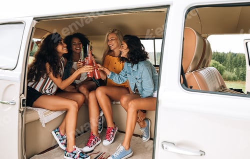 Preview: Smiling girlfriends cheering with bottles in a minivan