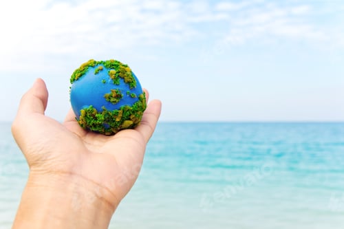 Preview: Hand Holding a Miniature Earth Globe by Ocean