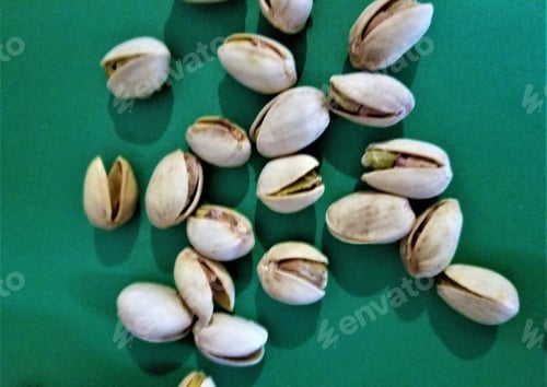 Preview: Handful of Pistachio Nuts on a Dark Green Background