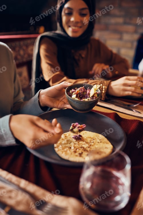Preview: Close-up of Muslim woman eating traditional food at dining table.