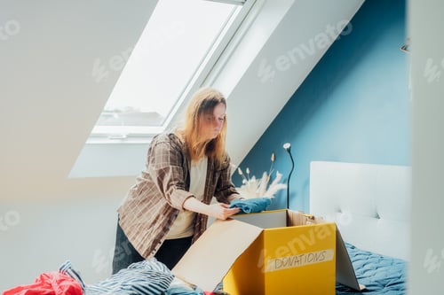 Preview: Woman selecting clothes from her wardrobe for recycling, donating to a Charity shop. Decluttering,